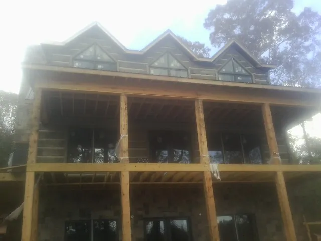 Dormers and porch framing on a large log home under construction — Roof Coating work by our crew in Mayesville