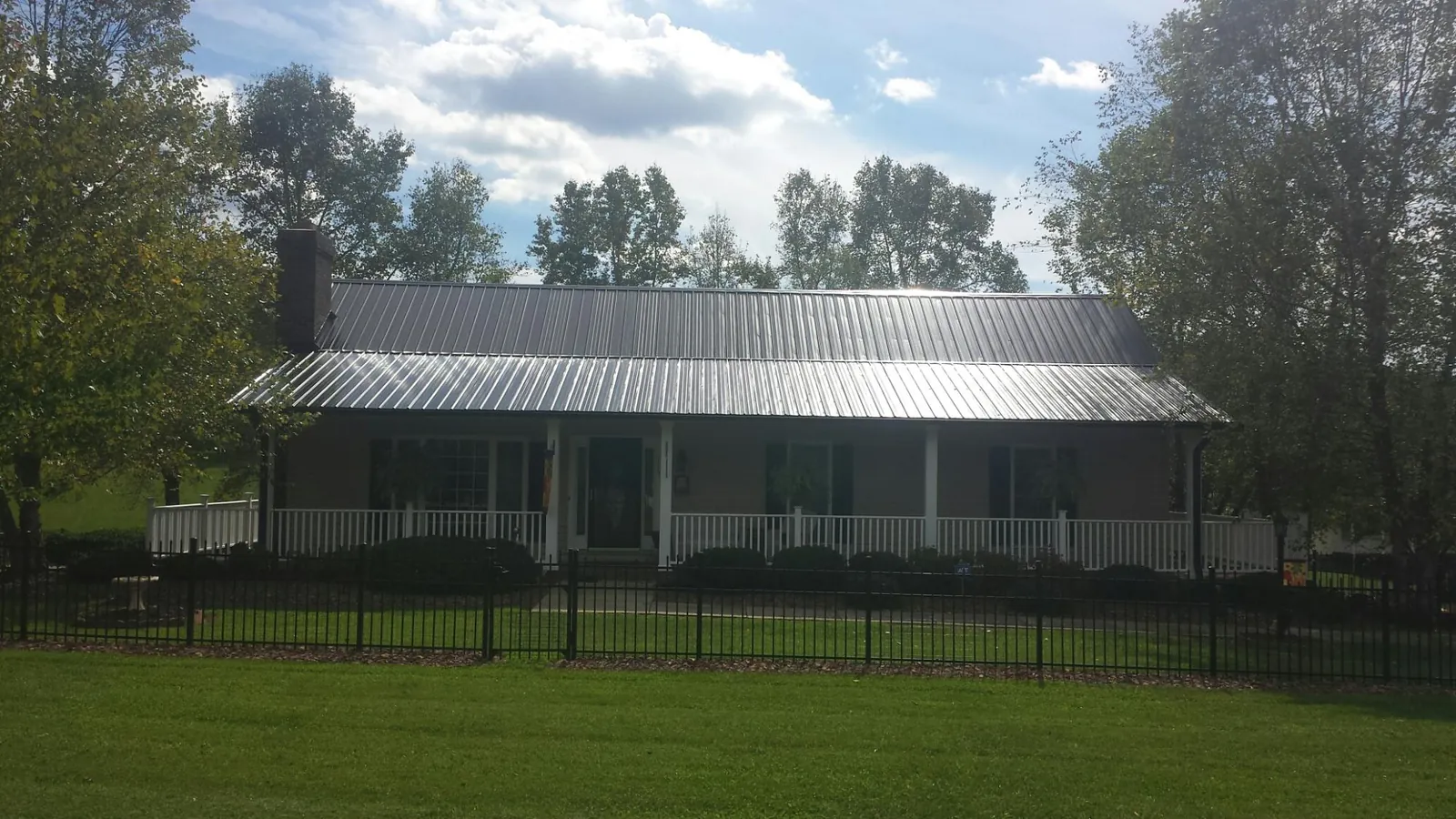 Gray metal roof on a brick ranch with a full width front porch — Gutter Guard Installation work by our crew in Mayesville