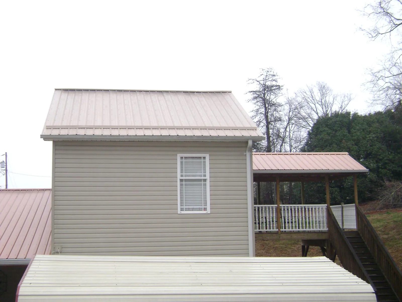 Tan metal roofs on a two story addition and attached porch, from a Roof Replacement job in Mayesville