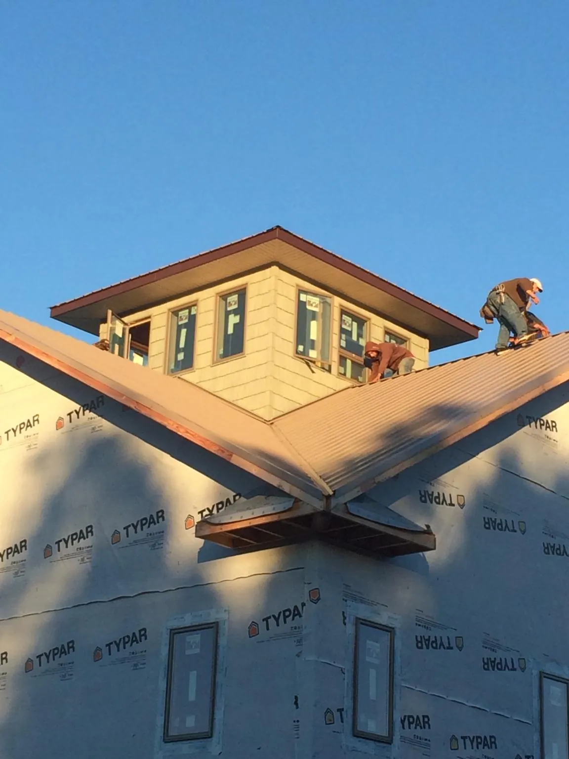 Roofers working around a rooftop cupola on a new metal roof at sunset — Roof Waterproofing in Mayesville by Roofing Brothers